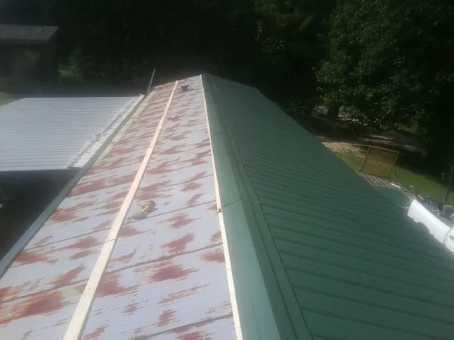 Old rusted panels beside newly installed green metal roofing — Wind Damage Roof Repair by Roofing Brothers in Tonganoxie