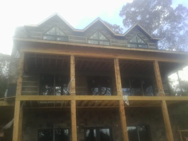 Dormers and porch framing on a large log home under construction — Roof Coating work by our crew in Tonganoxie