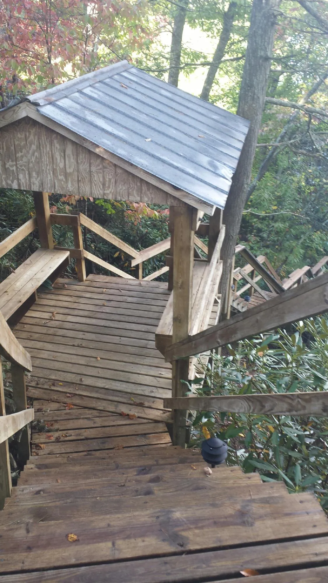 Metal roofed shelter over wooden steps on a wooded walkway — Skylight Repair & Installation work by our crew in Tonganoxie