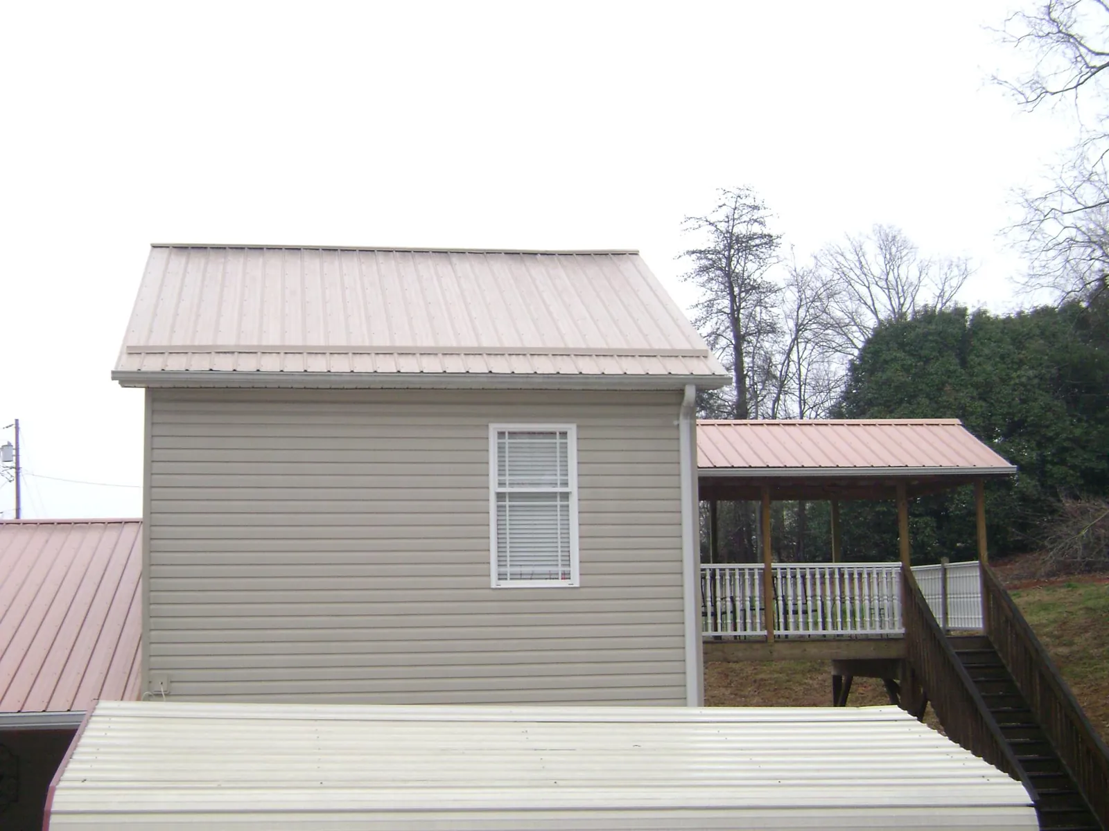 Tan metal roofs on a two story addition and attached porch, from a Roof Replacement job in Tonganoxie