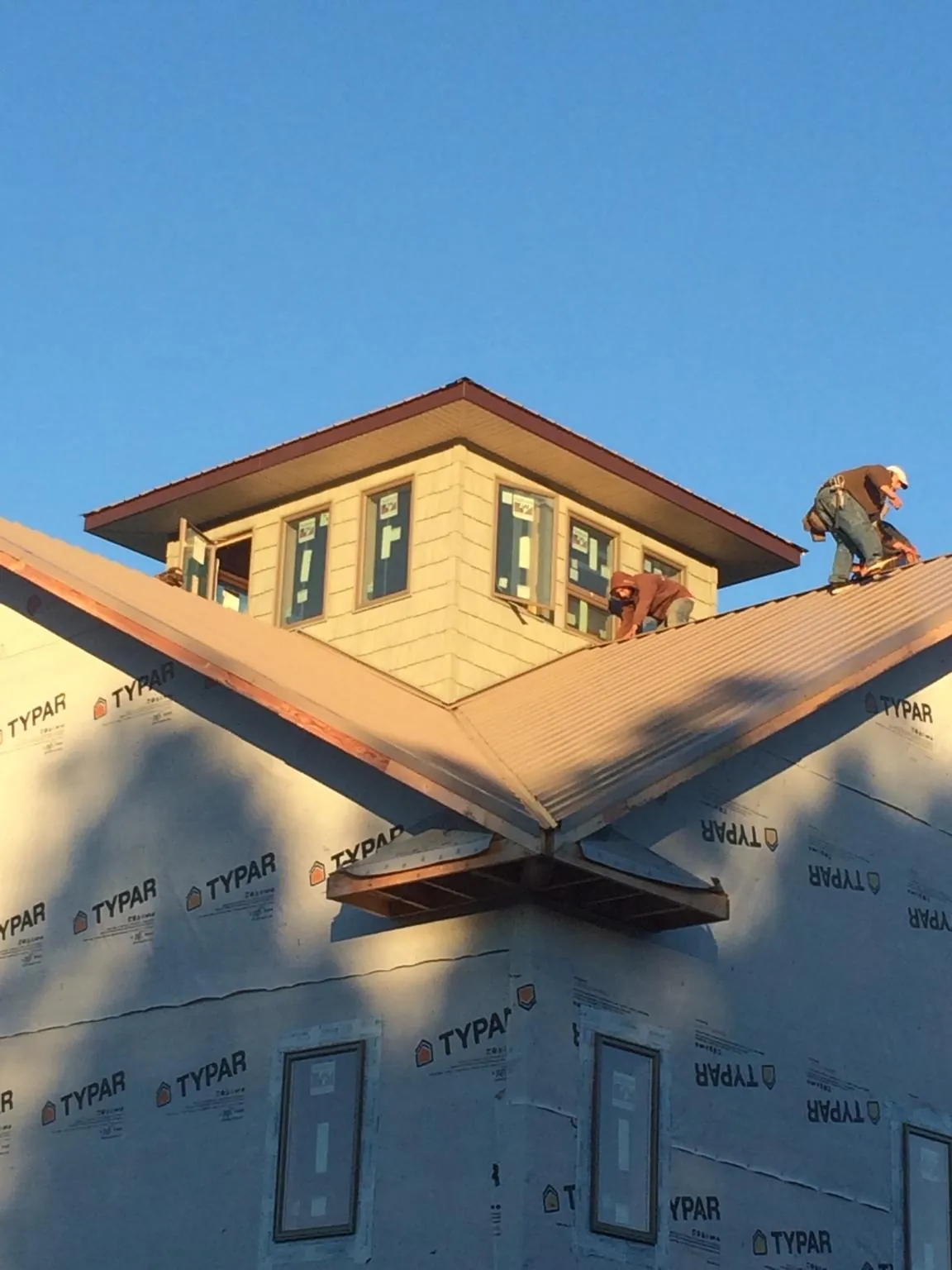 Roofers working around a rooftop cupola on a new metal roof at sunset — Roof Waterproofing in Tonganoxie by Roofing Brothers